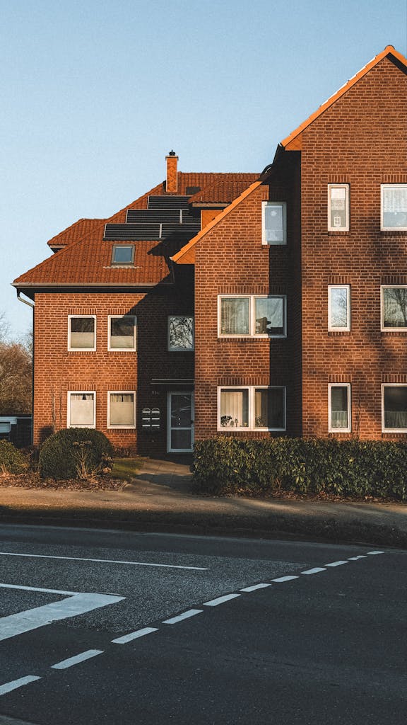 A classic brick house with gabled roof design under a clear blue sky, perfect for urban housing themes.